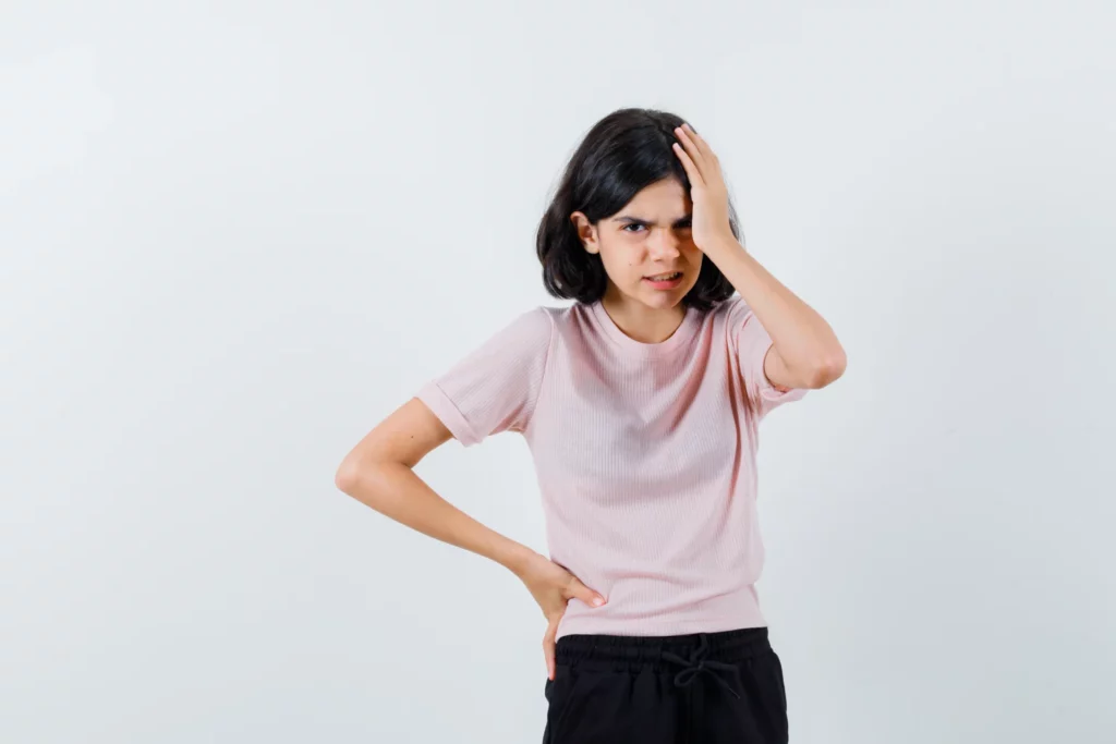 young girl putting hand head while holding hand waist pink t shirt black pants looking angry